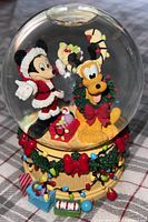Snow globe with Mickey Mouse in Santa outfit and Pluto with wreath, festive lights on base