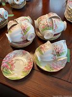 Overview of 12 teacups and 12 saucers arranged on table showing design and quantity