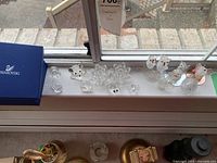 Overall view of nine crystal figurines and three spun glass birds on windowsill