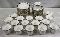 Full lot of Aynsley china cups and saucers with dessert bowls in back row, arranged on a table.
