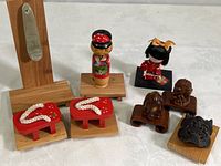 All items grouped on table, showing soapstone object, painted kokeshi doll, geisha doll, slippers, metal mask, and carved wooden animals