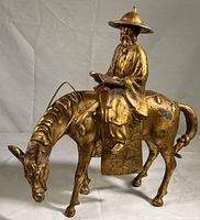 Full view of gilt cast iron scholar riding a horse sculpture, showing the entire piece from side angle.