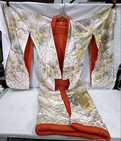 Front view of the large kimono robe showing the full embroidery pattern of pine branches and birds with an orange lining.