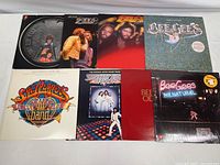 Eight vintage vinyl albums arranged, including Bee Gees classic albums and Beatles Sgt Pepper's album with accompanying poster included.