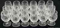 Eighteen glasses arranged in rows on black background
