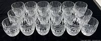 Eighteen glasses arranged in rows on black cloth