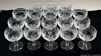 Eighteen crystal sherbet glasses arranged on black background