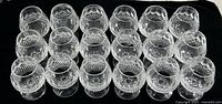 Group of 18 brandy glasses arranged in rows on a black background