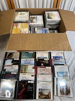 Open box showing over 100 classical music CDs stacked inside and some arranged in front of the box