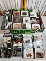 Box filled with approximately 45+ classical music CDs with jewel cases and some box sets, showing front covers and spines with names of composers and works.