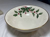View showing the holly and ivy design inside the white ceramic bowl with gold trim.