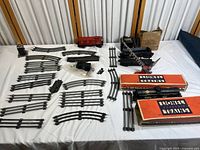 Overall layout of the train pieces including locomotives, railroad cars, multiple curved and straight track sections, and track switches spread on a white surface.