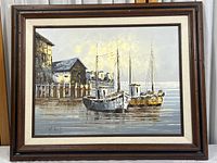 Framed oil painting showing two boats docked near boathouses on calm water, signed by H. Gatti.