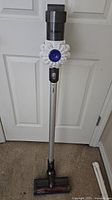 Full view of Dyson V6 cordless vacuum cleaner upright showing wand and cleaner head.