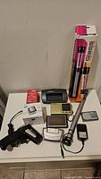 Overview of the assorted electronics on table including metal detector, GPS, scanner, small devices, and power adapter
