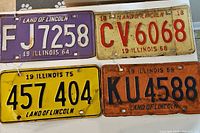 Four vintage Illinois license plates shown together, displaying different years and colors.