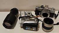 Full lot with various vintage and digital cameras plus lenses and camcorder on plain surface