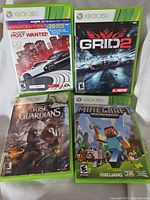 Four Xbox 360 game cases showing Need for Speed Most Wanted, GRID 2, Rise of the Guardians, and Minecraft Xbox 360 Edition covers.