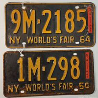Pair of worn New York World's Fair license plates from 1964 and 1965, black background with yellow-orange embossed characters, visible rust and chipping.