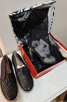 Two pairs of women's shoes shown, one pair outside box and a second pair inside an orange Hot Tomato box with tissue paper.