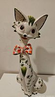 Front view of the tall ceramic cat showing facial features, texture, and painted motifs.