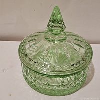 Top and side angle of pastel lime green Indiana Glass candy dish with geometric patterns and a pointed finial lid.