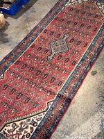Full length view of the Hamadan Persian rug showing the central medallion and surrounding geometric motifs on reddish background with blue border.
