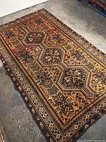 Full view of rug laid flat on concrete floor showing overall geometric medallion pattern and borders