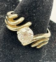 Close-up front view showing round diamond solitaire and twisted yellow gold band
