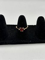Front view of ring on black velvet stand showing garnet heart and band profile