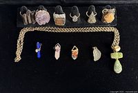 Display of six sterling silver Brutalist style rings and six unique crystal pendants on black background.