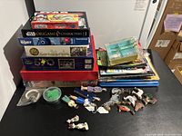 Overview of lot of puzzles and kid activity kits stacked and arranged on table showing various boxed puzzles and loose wooden figures.