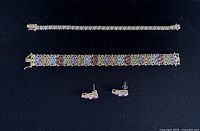 Top view of two bracelets and a pair of stud earrings on black background