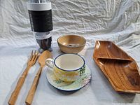 Overall shot showing all items in the lot including tea cup and saucer, cereal bowl, wooden servers, tray, and grater