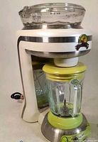 Front side view of the Margaritaville Margarita Maker showing the transparent ice chamber on top and the blender jar attached below with visible blades inside.