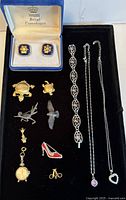 Overview of all costume jewelry including Royal Copenhagen cufflinks in box, various pins including turtles and birds, bracelet, and necklaces.