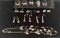 Full collection displayed on black jewelry holder and flat surface showing rings, earrings, and necklace with purple stones and beads
