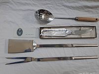 Full view of BBQ utensils including spatula, fork, poultry shears in box, and slotted spoon