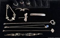 Overview of lot on black velvet: bracelets, brooches, rings and necklaces.