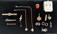 Overview of all sterling silver jewelry and accessories on black background including necklaces, rings, tie clips, pins, and earrings.