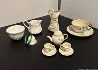 Front view of all miniature Irish china pieces arranged on black surface showing detailed porcelain.