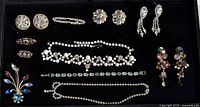 Display of the entire vintage jewelry lot with 11 sparkly pieces on black background showing condition and style of each item.