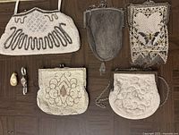 Top view of five vintage purses arranged on floor showing beadwork, mesh details, and ribbon and metal chain straps, and two vintage watches