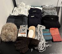 Clothing and accessories including nightgowns, tops, gloves, scarves, compression socks, and fuzzy hat displayed on table