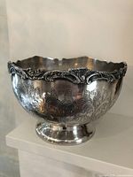 Side view of silverplate on copper bowl showing ornate sculptural rim and detailed rose engravings on the body