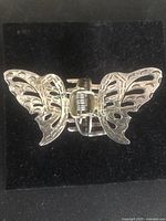 Top view showing the butterfly silver design with intricate wing cutouts and spring clasp