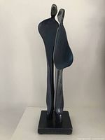 Front view of hand forged abstract steel sculpture with two standing figures on a square base.