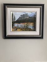 Full view of framed oil painting showing landscape with mountain, water, and trees.