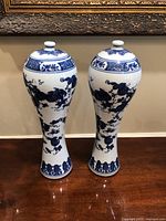 Front view of the pair of blue and white porcelain vases with lids, showing full height and shape.