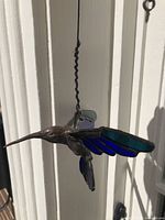 Side angle view of the bronze hummingbird with stained glass wings showing detail and hanging wire.